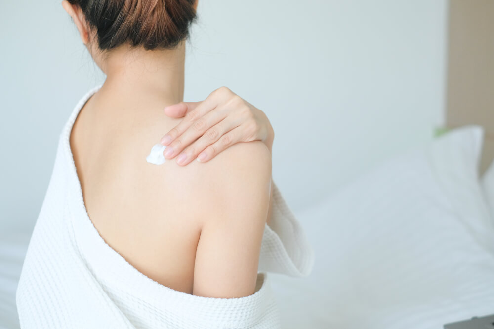 Woman applying cream to back