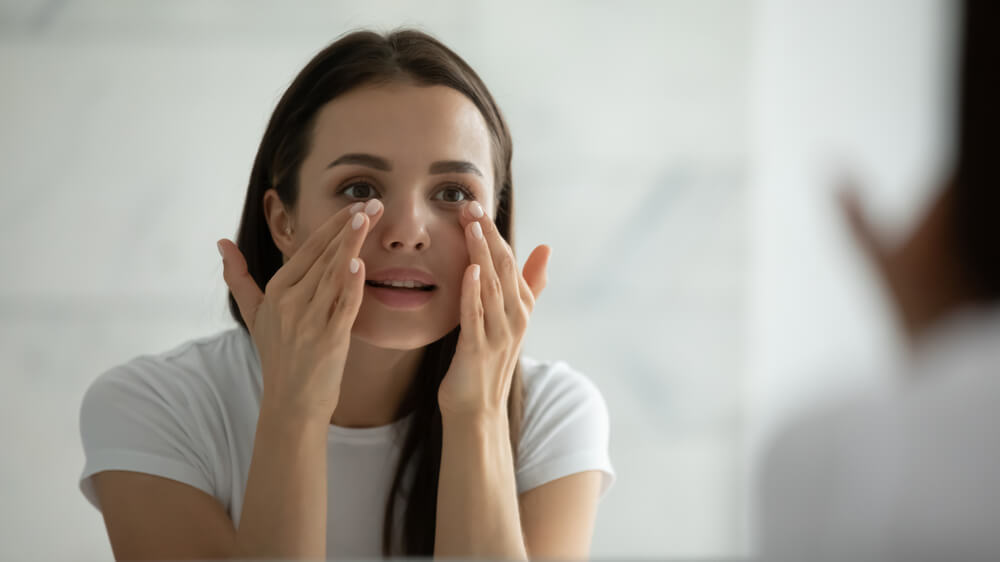 Woman looking at skin in mirror