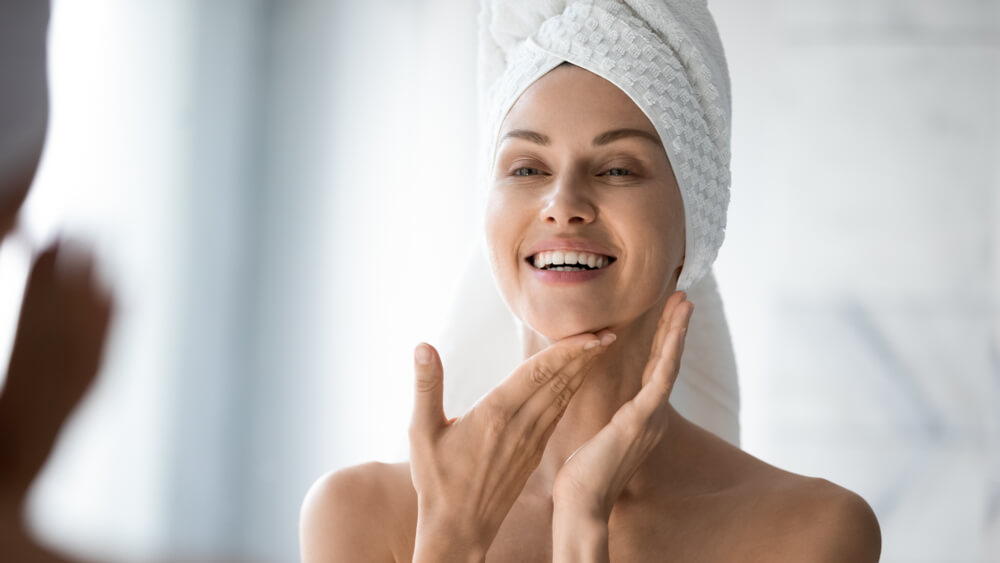 Woman looking at skin in mirror