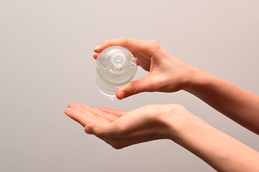 Woman holding alcohol in skincare bottle