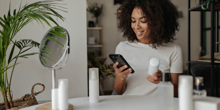 Woman holding skincare product and looking at phone