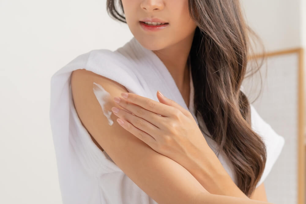 Woman using body butter on arm