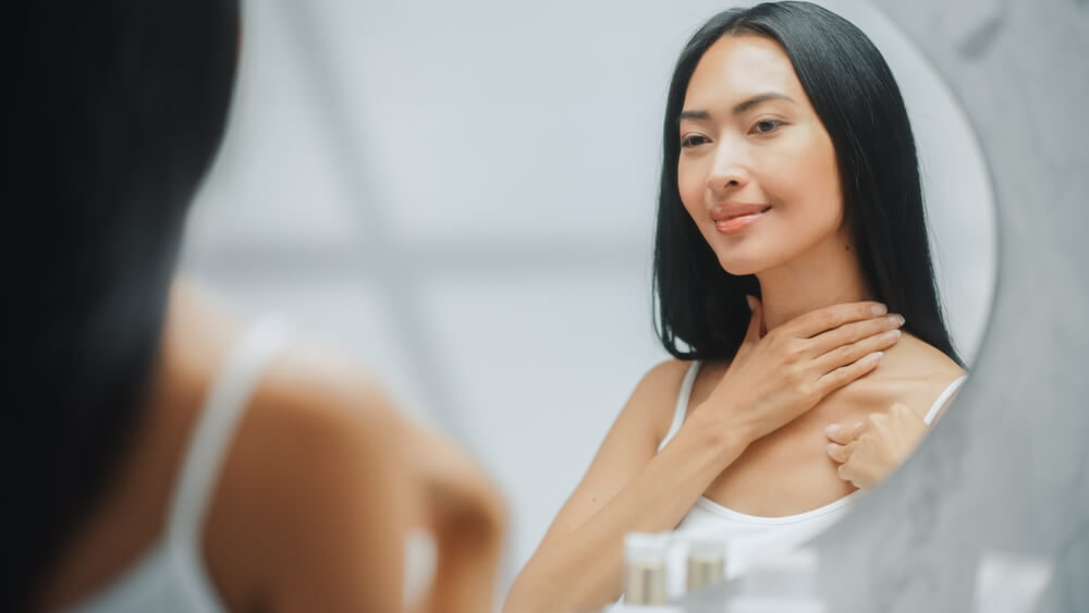 Woman looking at neck skin in mirror