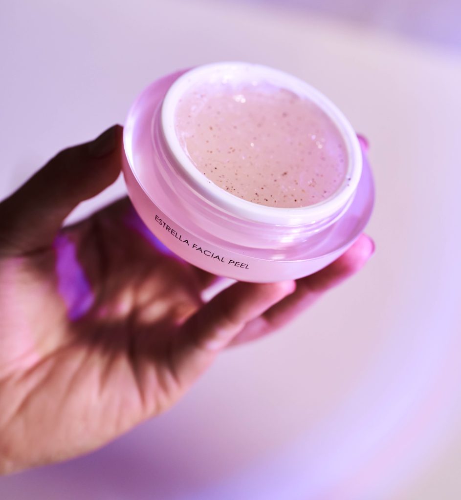 Hand holding an open jar of Celestolite's Estrella Facial Peel