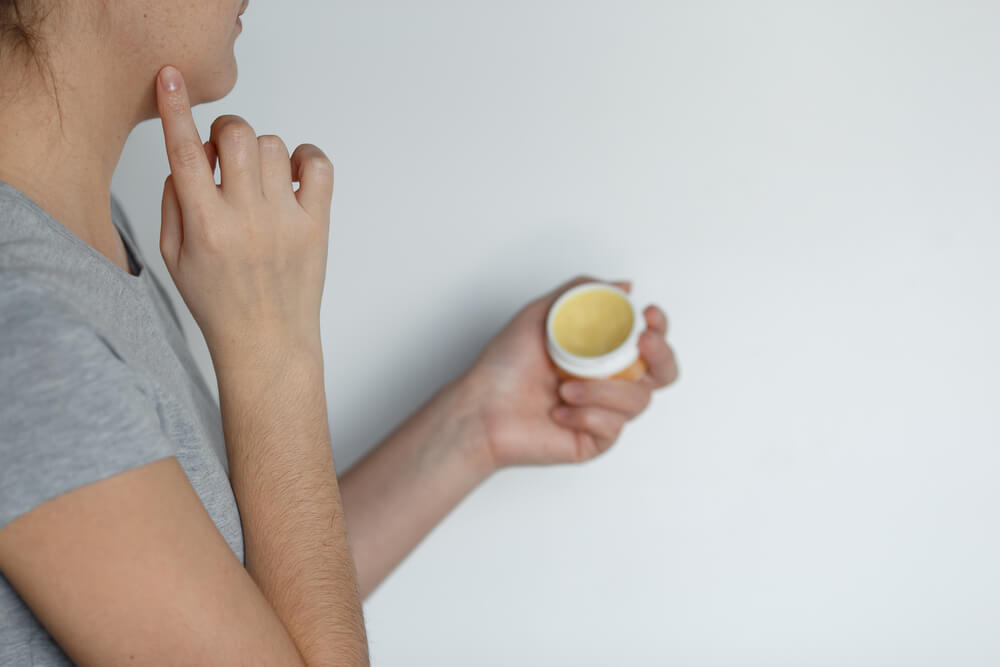 Woman applying petroleum jelly to face