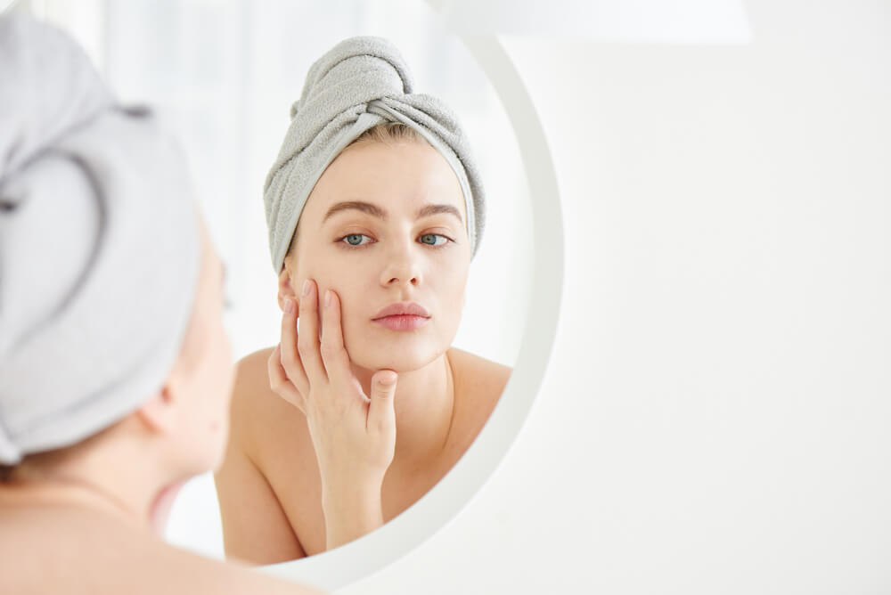 Woman looking at skin in mirror