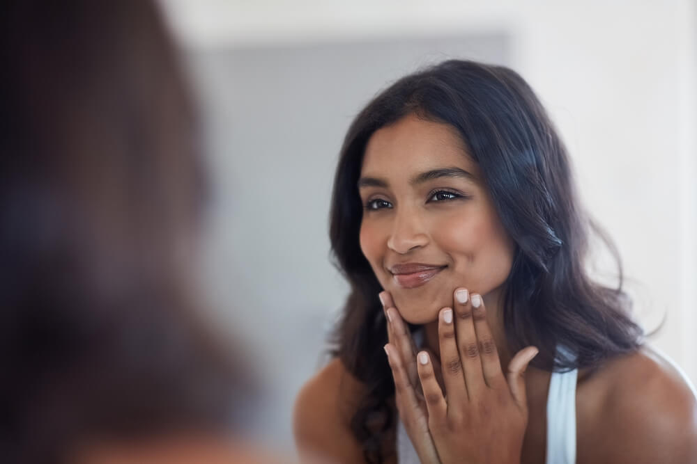 Woman looking at skin in mirror after using Celestolite syringe