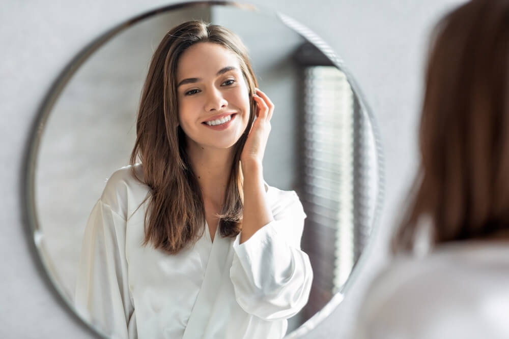 Woman looking at skin in mirror