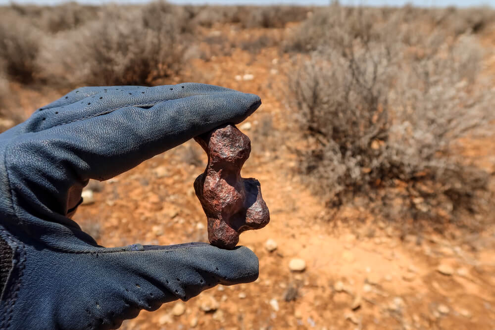 Hand holding meteorite in desert