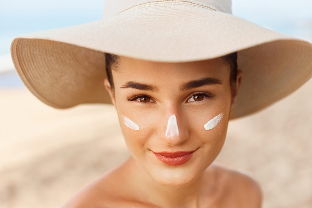 woman in hat with moisturizer on face